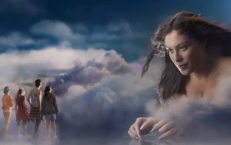 Atriz A Maia surge gigante em meio a fundo de nuvens e olha para os protagonistas de Quanto Mais Vida, Melhor