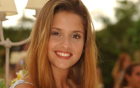 A atriz Giselle Policarpo caracterizada como Elisa, sua personagem em Mulheres Apaixonadas (2003), sorrindo para foto em close