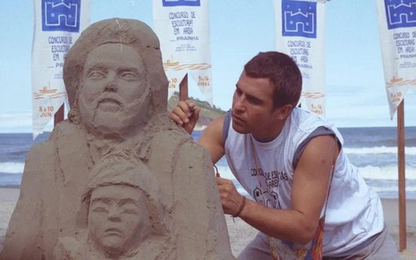 Marcos Frota em cena como Tonho da Lua em Mulheres de Areia, mexendo em boneco de areia na praia