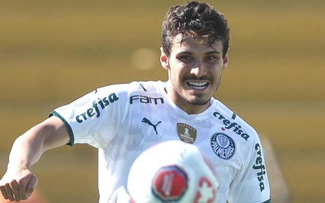 De uniforme branco do Palmeiras, Raphael Veiga pula para dominar a bola em jogo