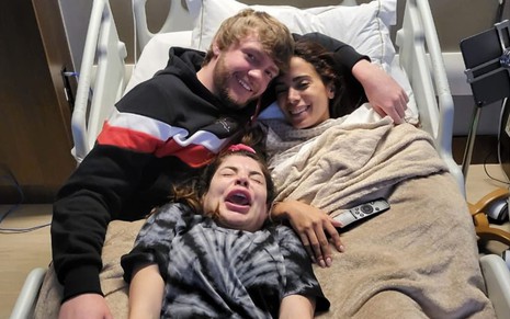 Imagem de Murda Beatz (à esq.), Anitta e Gkay (abaixo, no meio) deitados em uma cama de hospital