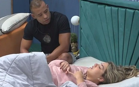 Mussunzinho e Karoline Menezes estão na cama do Power Couple; ele sentado e ela deitada, chorando