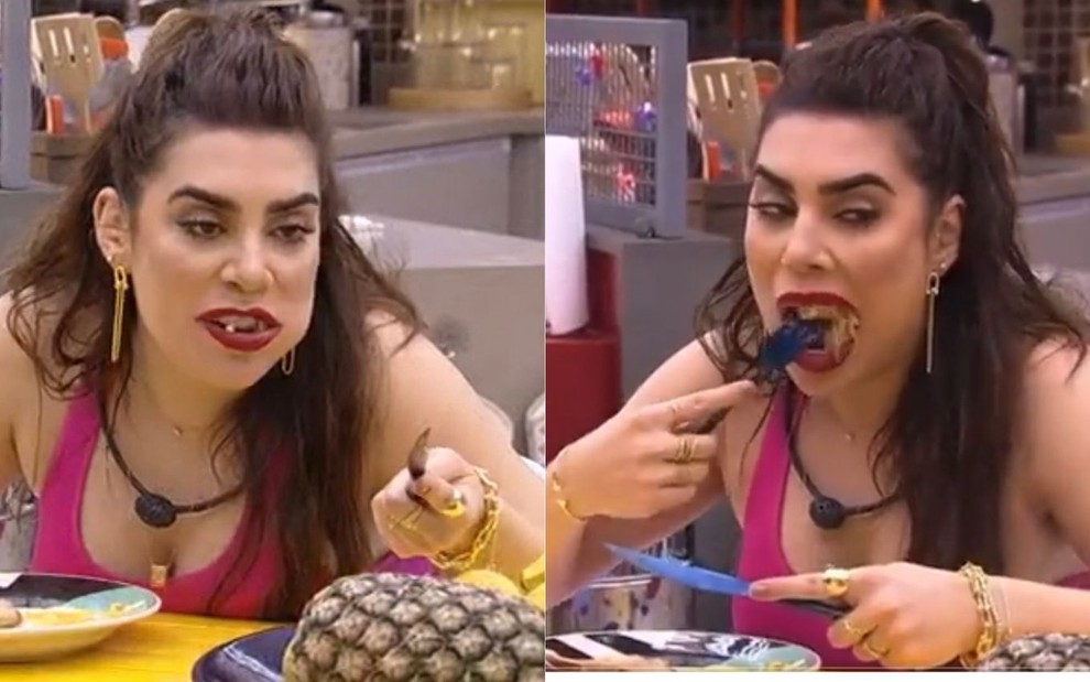 Naiara Azevedo comendo de boca aberta no BBB22, ela está sentada na cozinha vestindo uma regata rosa e com a boca cheia de comida