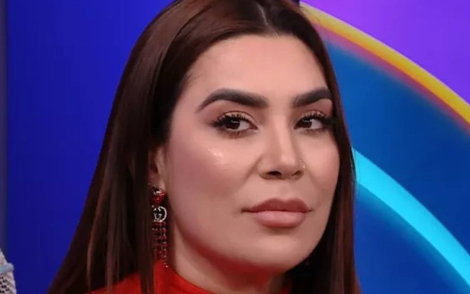 Naiara veste roupa vermelha e olha para o lado