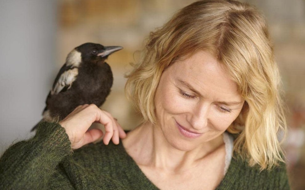 Naomi Watts aparece com um pássaro no ombro em cena como Sara Bloom no filme Um Milagre Inesperado