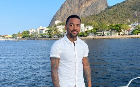 Imagem de Nego do Borel de camisa branca em frente ao mar no Rio de Janeiro