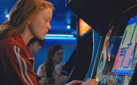 Max (Sadie Sink) jogando game antigo em cena de Stranger Things, série da Netflix