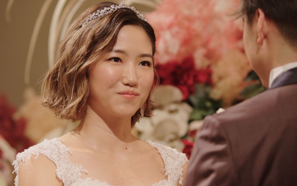 A participante Midori, de Casamento às Cegas Japão, sorri de frente para Wataru (de costas) em cena do casamento de Love is Blind Japan, da Netflix