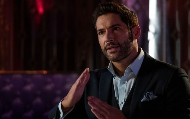 Tom Ellis em cena de série Lucifer: caracterizado como personagem, ator está de terno e gesticula com as mãos