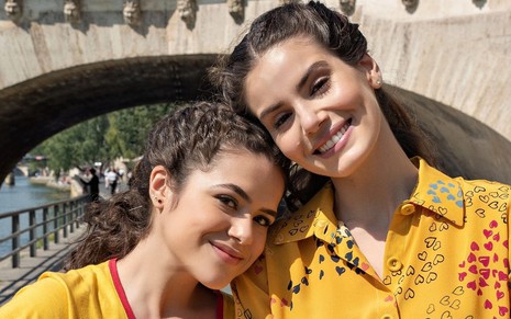 Maisa Silva e Camila Queiroz sorrindo abraçadas em foto durante as gravações da série De Volta aos 15 em Paris