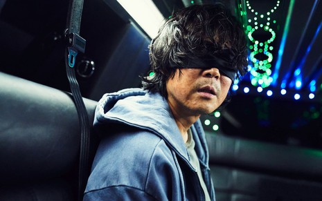 Lee Jung-jae está vendado dentro de um carro em cena de Round 6, da Netflix
