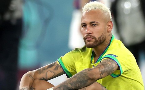 Neymar Jr está com a camiseta do Brasil, sentado no gramado