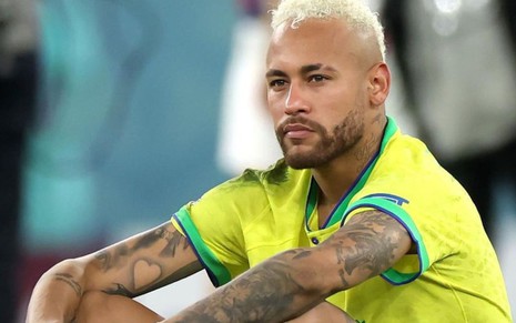 Neymar com a camisa da Seleção Brasileira sentado no campo em Doha, no Catar