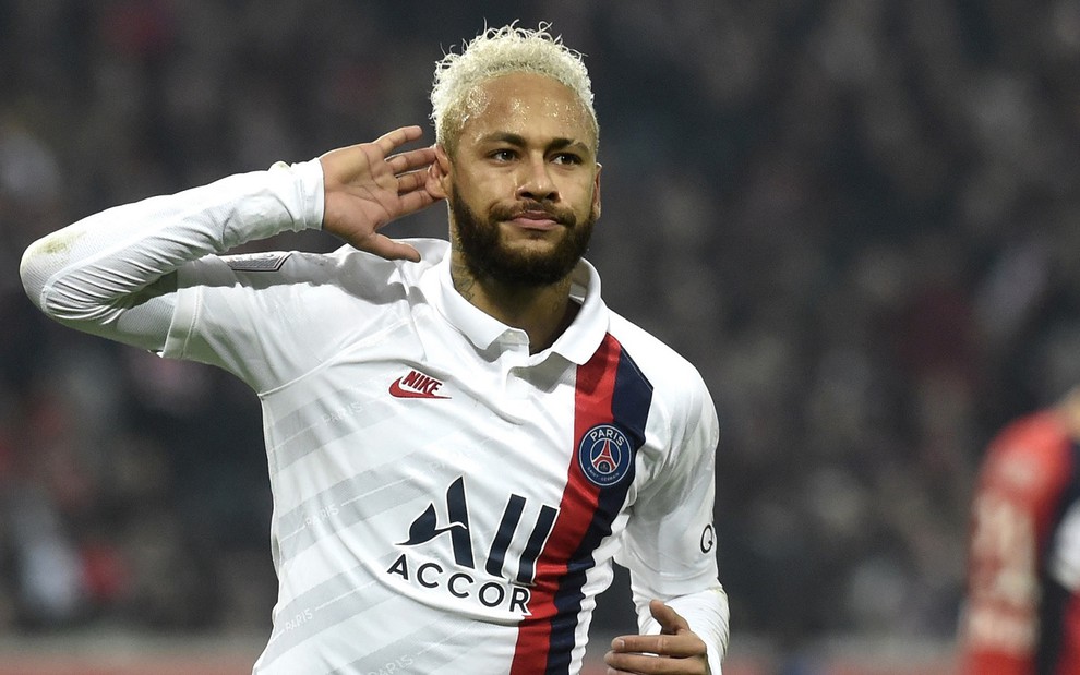 Neymar com uma camisa branca do PSG, em campo, pedindo para a ouvir o que a torcida está gritando durante jogo do Campeonato Francês