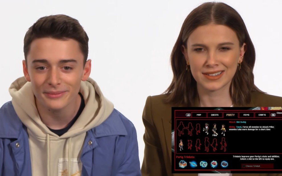 Imagem de Noah Schnapp e Millie Bobby Brown enquanto conhecem jogo de Stranger Things