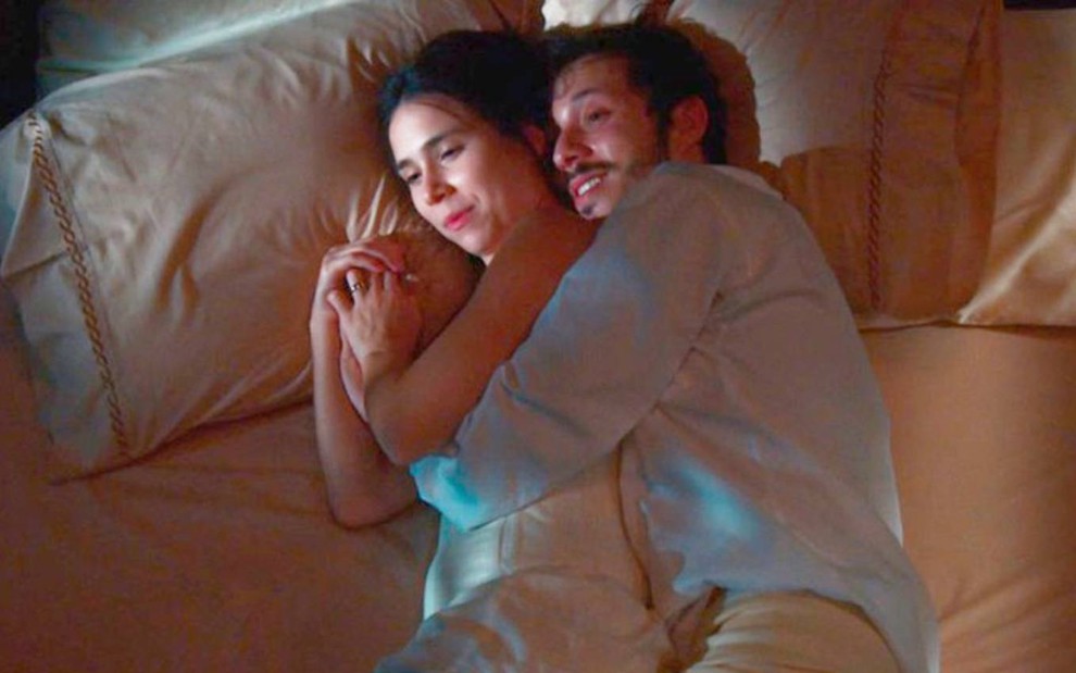 Atriz Daphne Bozaski surge sobre cama, abraçada ao ator João Pedro Zappa, em cena de Nos Tempos do Imperador