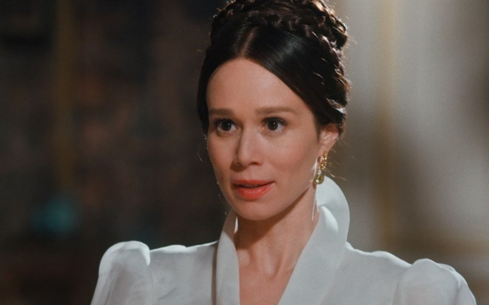 Luísa (Mariana Ximenes) está vestida de branco na sala da residência real em cena de Nos Tempos do Imperador