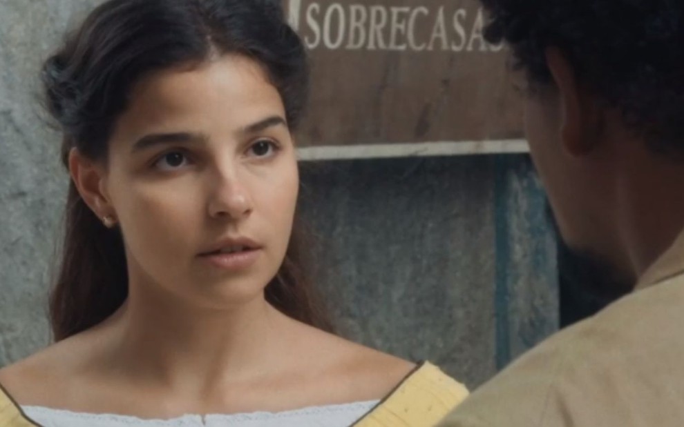 Pilar (Gabriela Medvedovski) está em pé em rua com Samuel (Michel Gomes) que está de costas na imagem, em cena de Nos Tempos do Imperador