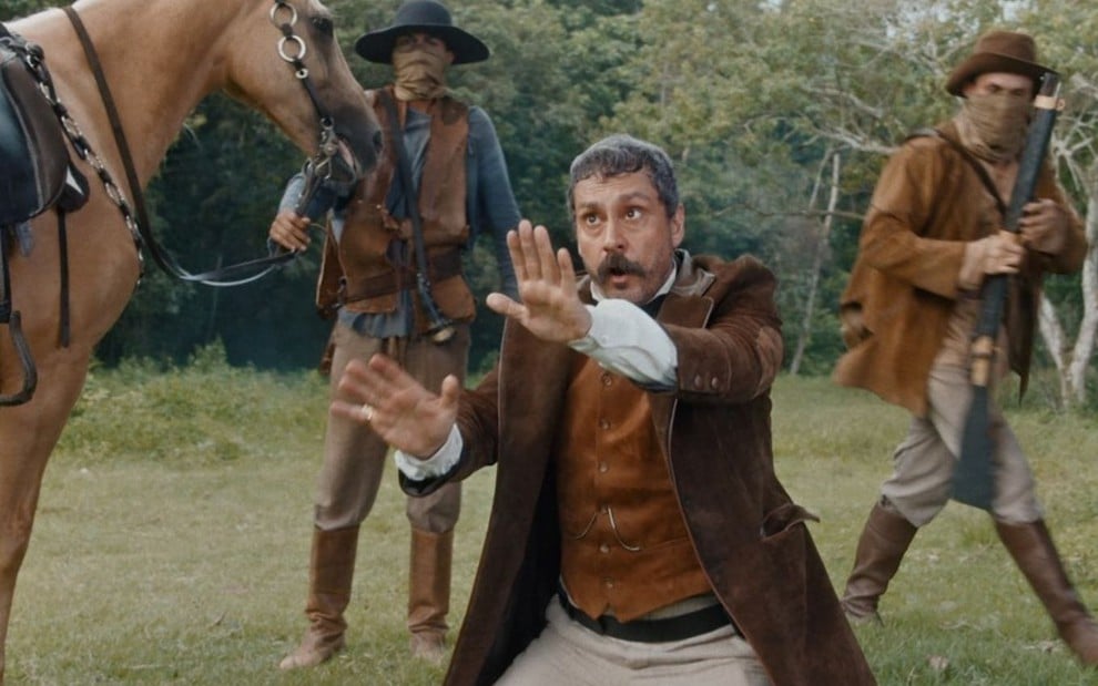 Tonico Rocha (Alexandre Nero) é cercado por jagunços com arma em cena de Nos Tempos do Imperador