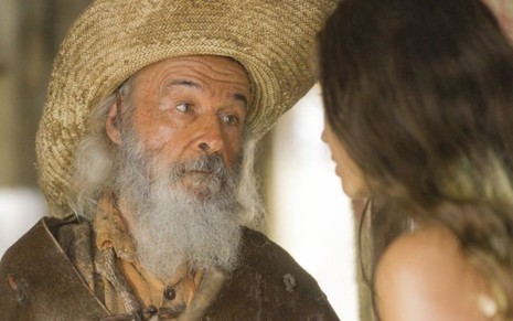 O ator Osmar Prado caracterizado como Velho do Rio, em frente à atriz Alanis Guillen, que aparece de costas na foto; ambos estão em cena da novela Pantanal