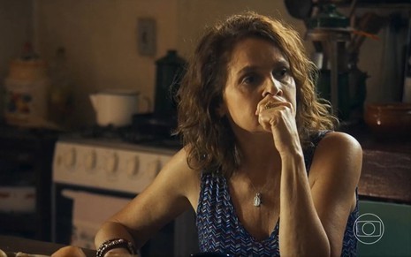 Em cena de Travessia, Drica Moraes está com a mão na altura da boca, pensativa