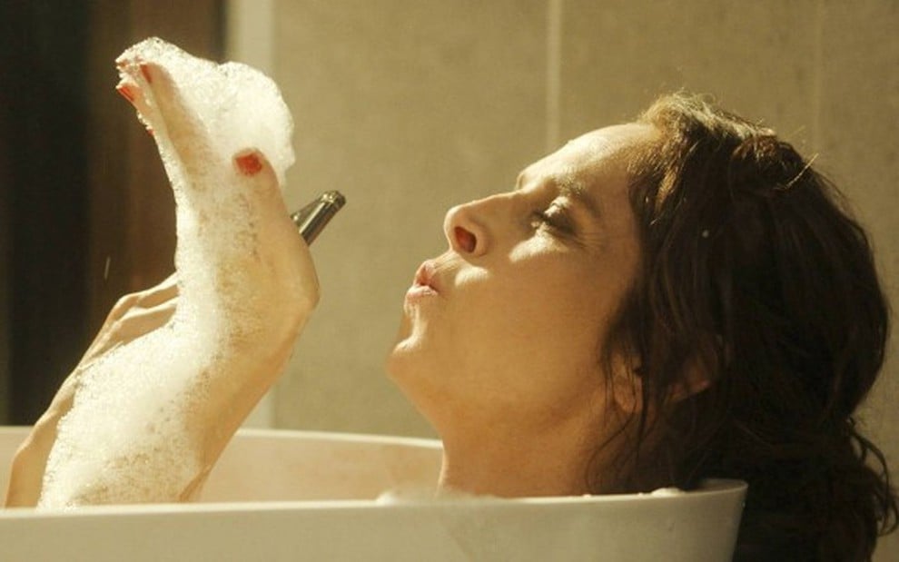 Em cena de Travessia, Drica Moraes está em uma banheira com a mão cheia de espuma