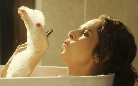 Em cena de Travessia, Drica Moraes está em uma banheira com a mão cheia de espuma