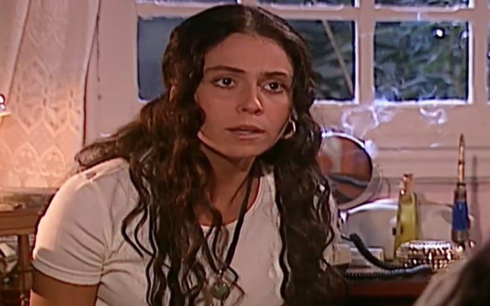 Giovanna Antonelli em cena de O Clone: caracterizada como Jade, atriz está com cabelos soltos, camiseta branca e olha aflita para alguém fora do quadro