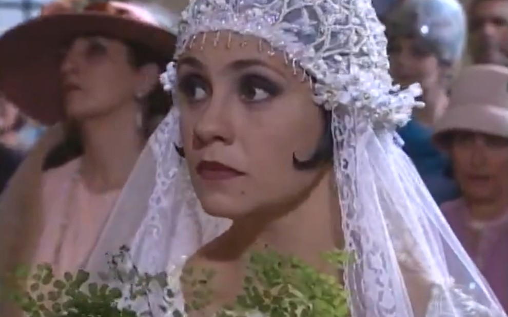 Adriana Esteves, caracterizada como Catarina, vestida de noiva, olha para o lado com deboche em cena de O Cravo e a Rosa