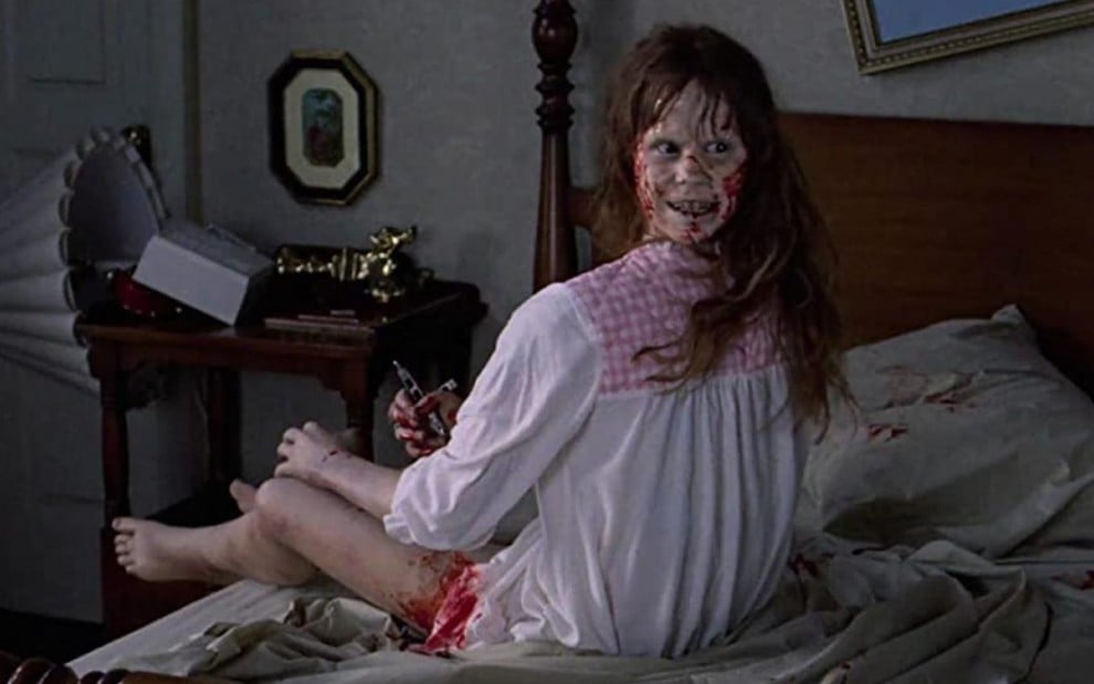 Linda Blair sentada na cama e com a cabeça virando ao contrário em cena do filme O Exorcista