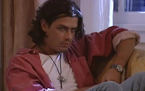 O ator Fabio Assunção com expressão séria, sentado num sofá em cena de O Rei do Gado
