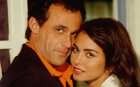 Os atores Oscar Magrini e Leila Lopes como Ralf e Suzane em O Rei do Gado; eles estão abraçados, olhando para o lado e posando para a foto