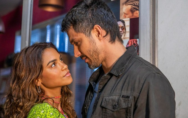 Lucy Alves está olhando para Romulo Estrela com ternura em cena de Travessia