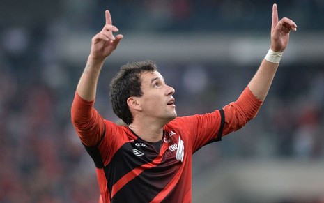 Pablo, do Athletico-PR, em campo com os braços para cima de uniforme vermelho com detalhes pretos