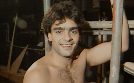 Guilherme de Pádua sem camisa, sorrindo em cenário de teatro, em 1991