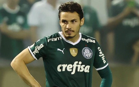 Raphael Veiga, do Palmeiras, parado com as mãos na cintura, vestindo camisa verde e shorts branco
