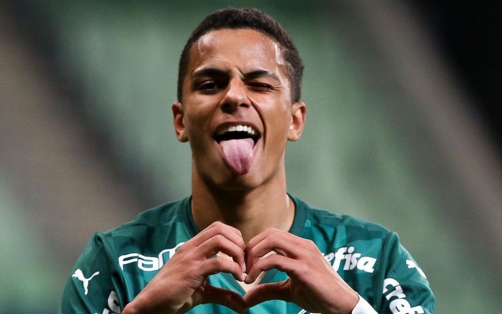 Jogador Giovani, do Palmeiras, veste uniforme verde e comemora gol fazendo sinal de coração com as mãos
