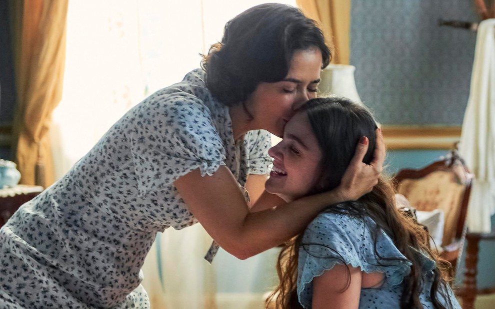 Heloísa (Paloma Duarte) beija a cabeça de Olívia (Debora Ozório) em cena da novela Além da Ilusão