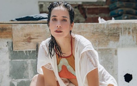 A atriz Paloma Duarte de cabelo molhado, maio e camisa branca, olha para câmera