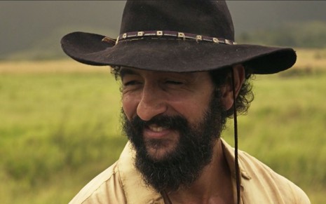 Joventino (Irandhir Santos) usa uma camisa clara e chapéu em cena de Pantanal, novela das nove da Globo