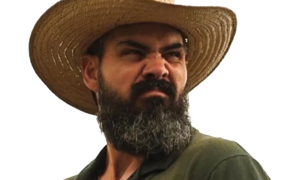 Juliano Cazarré em cena de Pantanal usando chapéu de peão; ator está franzindo o nariz com cara de insatisfação