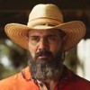 O ator Juliano Cazarré como Alcides em Pantanal; ele está de chapéu, olhando para frente com cara de quem vai começar a chorar