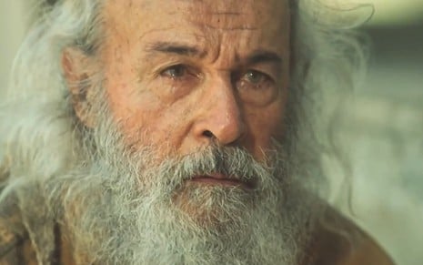 Osmar Prado está com barba e cabelos brancos crescidos em cena da novela Pantanal, novela na qual ele interpretou o Velho do Rio