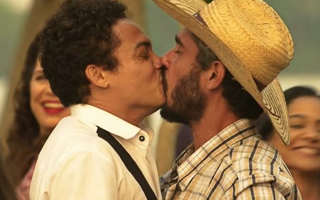 Os atores Silvero Pereira e Thommy Schiavo como Zaquieu e Zoinho em Pantanal; eles estão se beijando de olhos fechados