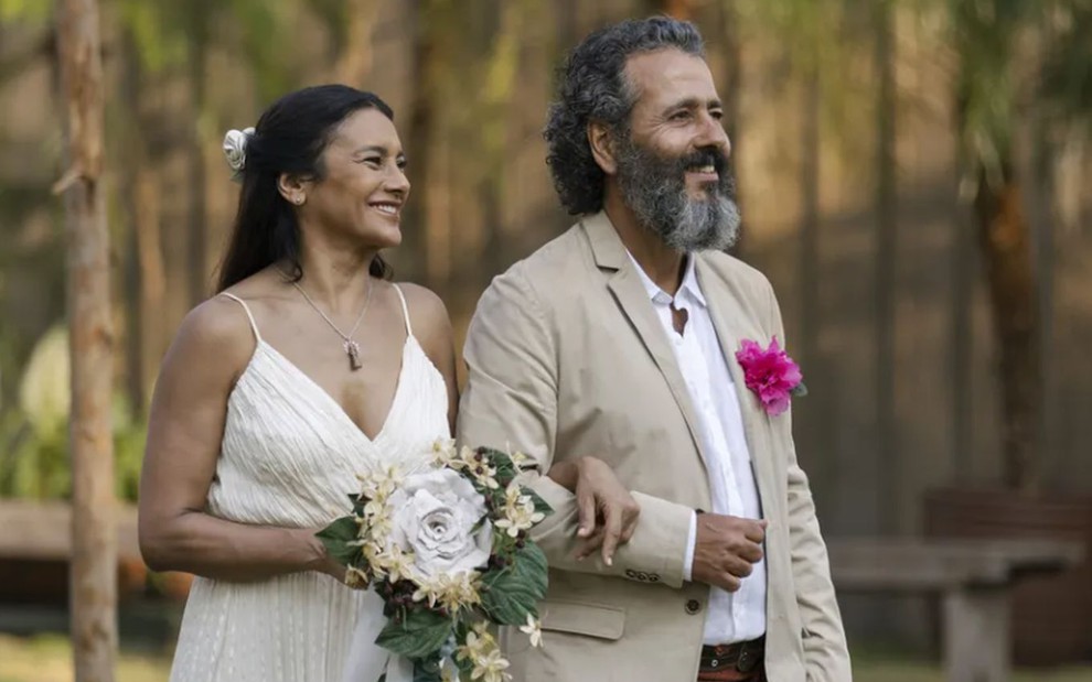 Os atores Dira Paes e Marcos Palmeira como Filó e José Leôncio; eles estão vestidos de noivos e de braços dados, de lado, olhando para a frente e sorrindo, enquanto ela segura um buquê