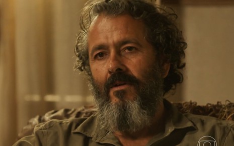 O ator Marcos Palmeira como José Leôncio em Pantanal; ele está sentado, olhando para frente com cara de reflexivo