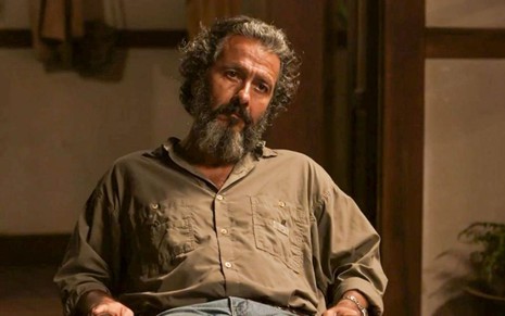 O ator Marcos Palmeira como José Leôncio em Pantanal; ele está sentado, olhando para frente com cara de cansado