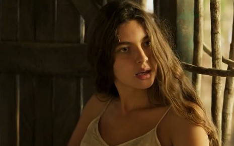 A atriz Alanis Guillen como Juma em Pantanal; ela está sentada, olhando para o lado com cara de surpresa