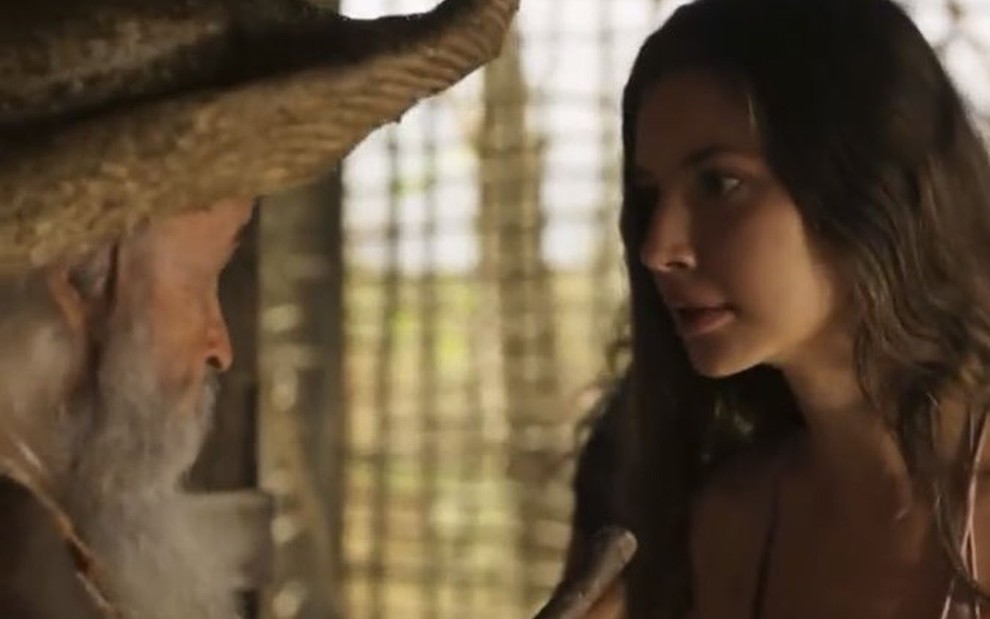 Em cena de Pantanal, Osmar Prado conversa com Alanis Guillen com olho no olho; eles estão no cenário da tapera da novela das nove da Globo