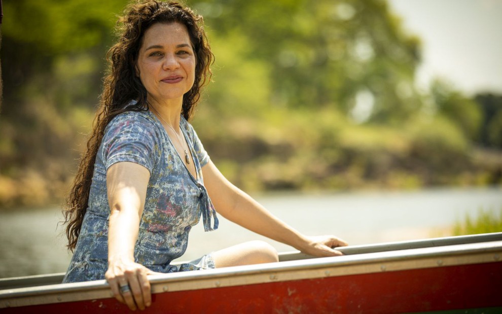 Isabel Teixeira, caracterizada como sua personagem em Pantanal, está feliz em um barco